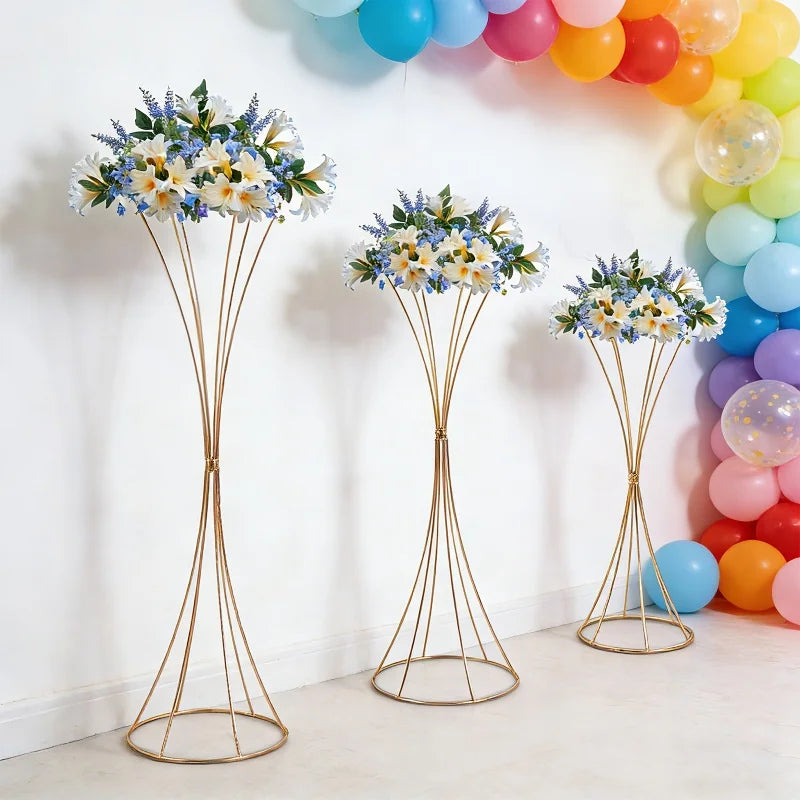 Trois supports floraux dorés en sablier dans un décor de fête