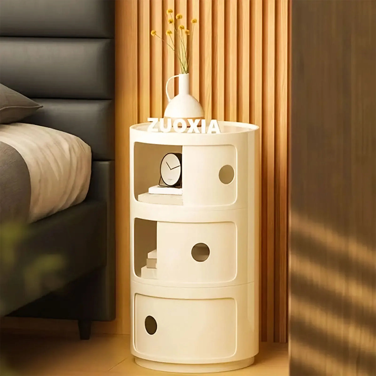Table de chevet ronde avec compartiments à portes coulissantes — près d’un lit