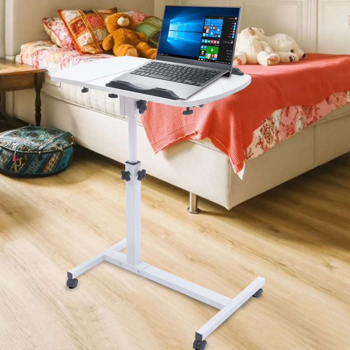 Bureau mobile blanc à plateau inclinable pour ordinateur — près d’un lit