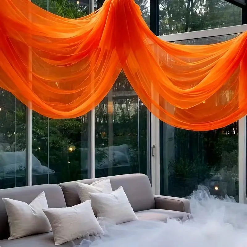 Voilages en tulle orange, drapés suspendus en grande arche pour décoration d’événement.