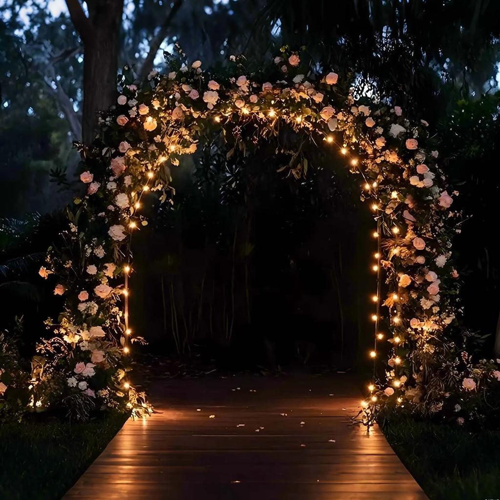 Arche arrondie dorée en métal : exemple de mise en lumière au jardin.