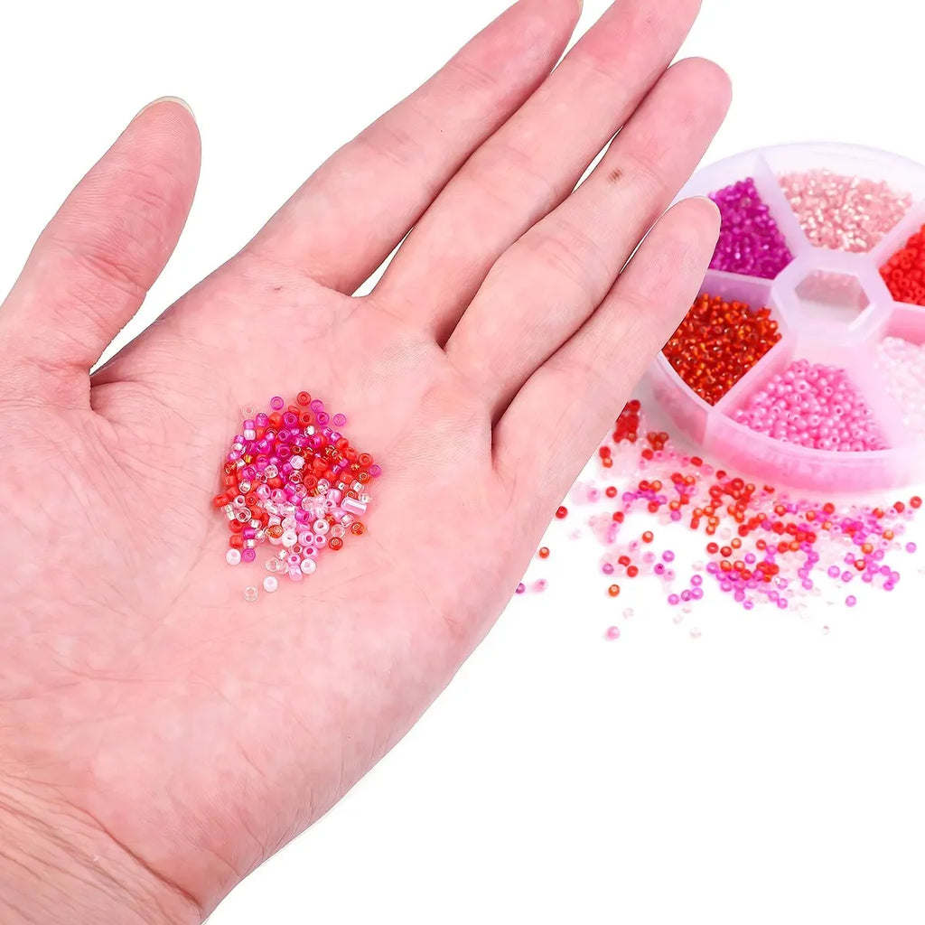 Perles de riz en verre multicolores en vrac, dans la main, avec compartiments.
