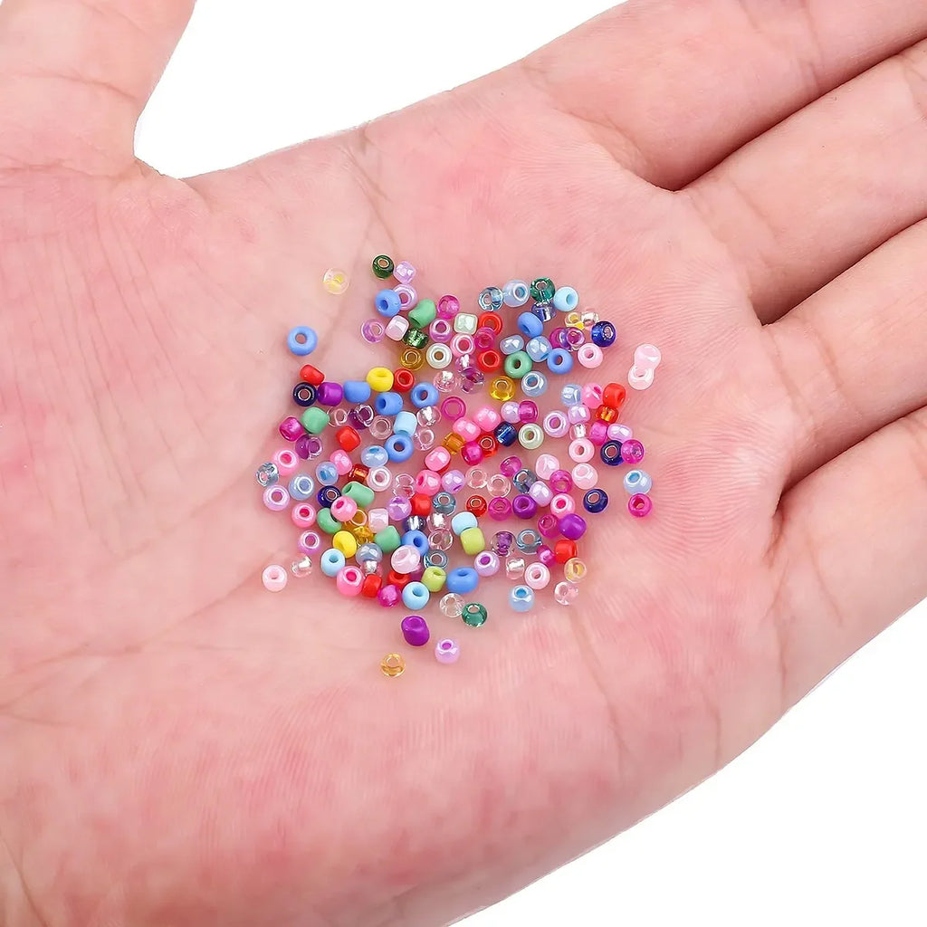 Perles de riz en verre multicolores en vrac, dans la paume.
